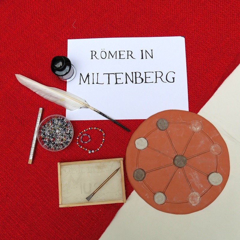 Verschiedene Gegenstände des Workshops zu den Spuren der Römer in Miltenberg; Federkiel und Tintenfass, ein Spielbrett und ein Armband