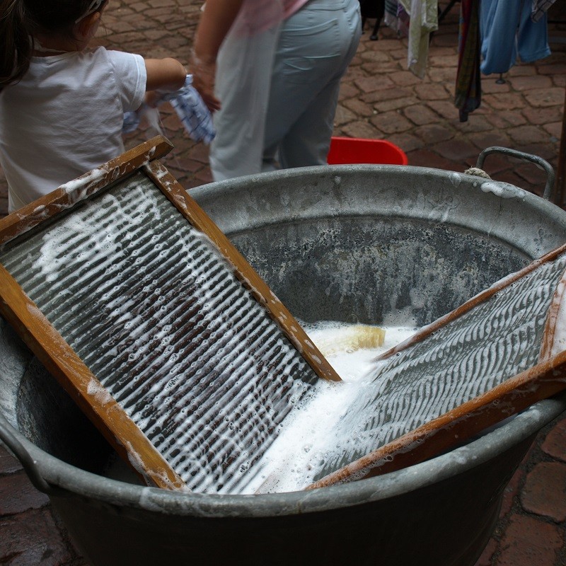 Zwei Waschbretter liegen in einer Waschwanne mit seifigen Wasser